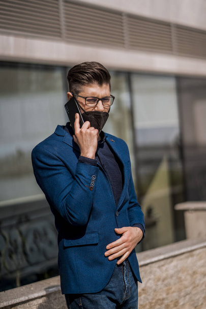 Moderne zakenman met notebook praten op mobiele telefoon in stedelijke plaats - Foto, afbeelding