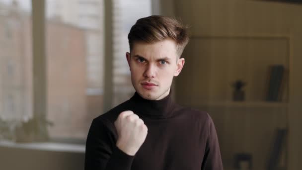Portrait millennial caucasian guy student male manager leader angry man showing danger gesture with hand shaking fist threatening warns of rage aggression violence standing indoors looking at camera - Video, Çekim
