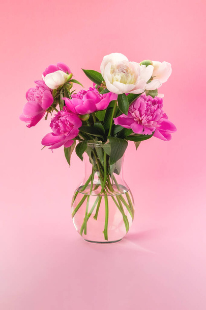 Bouquet of pink and white peonies in a glass vase on a pink background. Floral card design - Foto, Imagem