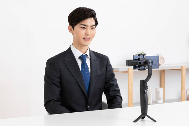 Asian young man in suit preparing untact online interview using smartphone - Foto, imagen