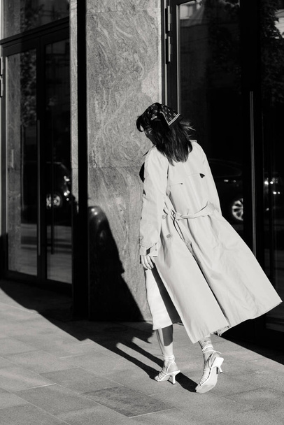 Beautiful young caucasian woman wearing trench coat walking in the city - Zdjęcie, obraz