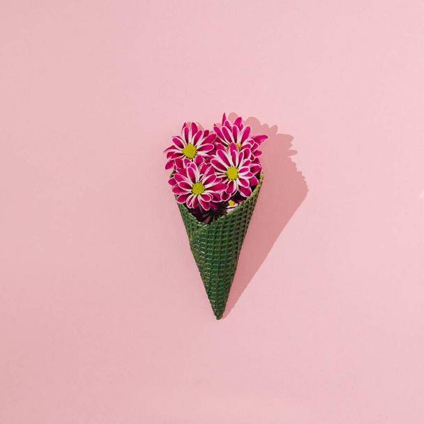 A bouquet of fuschia zinnias emerging from a green ice cream cone on a pastel pink background. Creative summer vibes concept. Lovely artistic nature and holidays vision. - Foto, Imagem