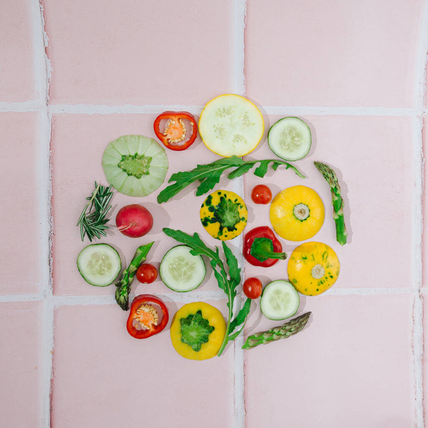 An infographic made of seasonal vegetables in round shape on a pale pink kitchen tales.. Healthy food concept. Vegetarian artistic creative design. Flat lay - Zdjęcie, obraz