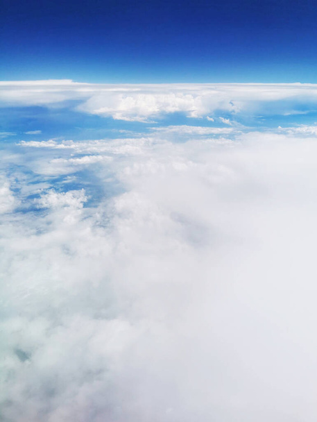 A mesmerizing view from above dense fluffy clouds in the blue sky - perfect for wallpapers - Foto, Imagen