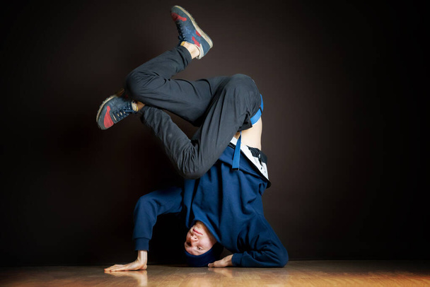 hip hop χορεύτρια εκτελέσει headstand ανάποδα στο σκοτεινό στούντιο β - Φωτογραφία, εικόνα