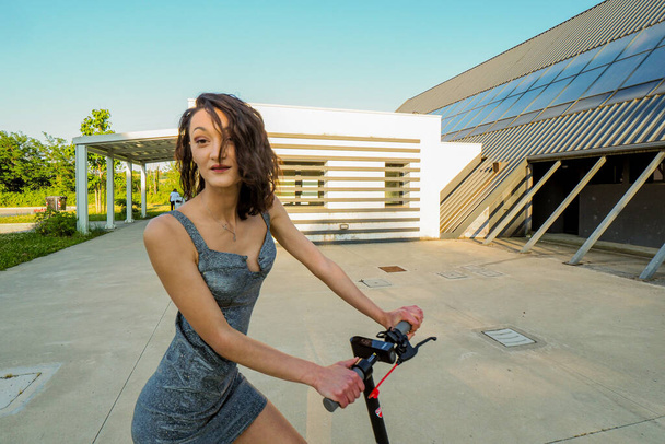 PIACENZA, ITALY - Jun 02, 2021: Young hispanic thin girl dressed elegant riding an  electric scooter - Foto, imagen