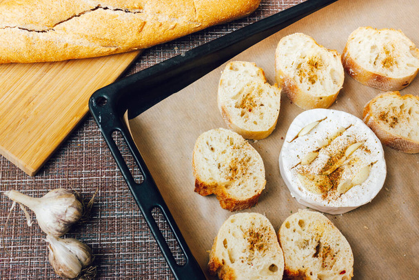 DIY sült sajt camembert utasítás lépésről lépésre. lépés tegyük a kenyeret és a camembert-et sütőlapra sütőpapírral, és adjuk hozzá a fűszereket. sajt fehér penész.penészes sajt. - Fotó, kép