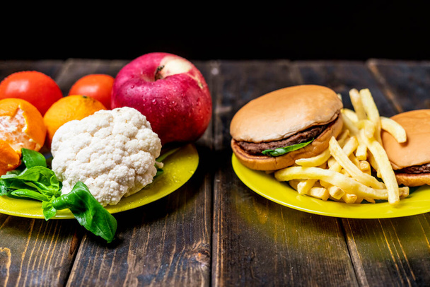 junk food of gezonde groenten en fruit op donker houten tafel geïsoleerd b - Foto, afbeelding