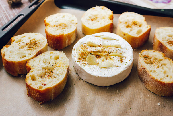 DIY ψημένο τυρί camembert οδηγίες βήμα προς βήμα. βήμα 3 Τοποθετήστε το ψωμί και το καμαμπέρ σε ένα ταψί με λαδόκολλα και προσθέστε τα μπαχαρικά. τυρί με λευκό mold.moldy τυρί. - Φωτογραφία, εικόνα