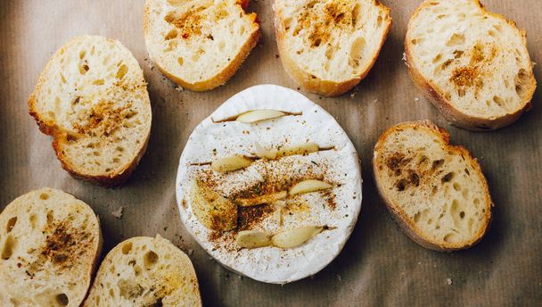 DIY ψημένο τυρί camembert οδηγίες βήμα προς βήμα. βήμα 3 Τοποθετήστε το ψωμί και το καμαμπέρ σε ένα ταψί με λαδόκολλα και προσθέστε τα μπαχαρικά. τυρί με λευκό mold.moldy τυρί. - Φωτογραφία, εικόνα