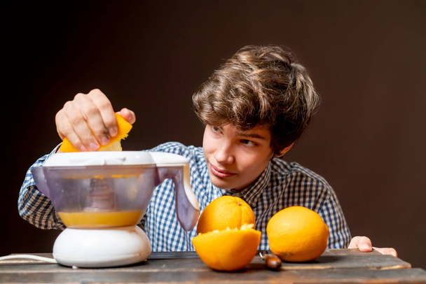 Genç adam taze portakallı meyve suyu yapıyor. - Fotoğraf, Görsel