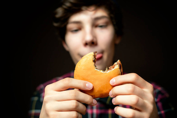 самец держит укушенный чизбургер и страстно ест его f - Фото, изображение