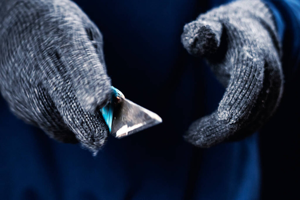 Маньяк в перчатках держит острый нож за спиной и в кармане болт - Фото, изображение