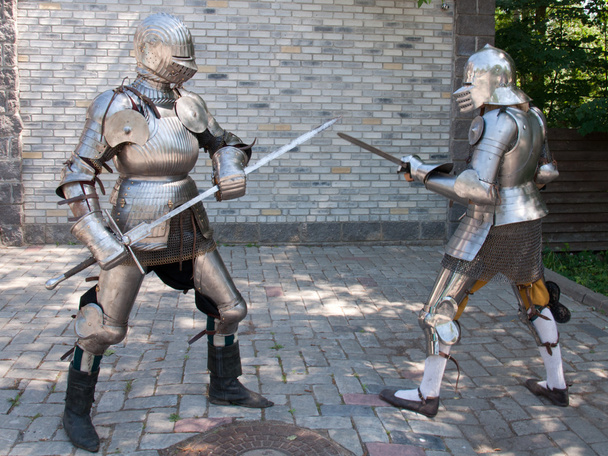 Dos caballeros en la antigua armadura de metal de pie cerca de la pared de piedra
 - Foto, imagen