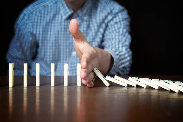 Nahaufnahme männlicher Stop-Dominofall mit Hand auf Tisch auf dunklem Hintergrund - Foto, Bild