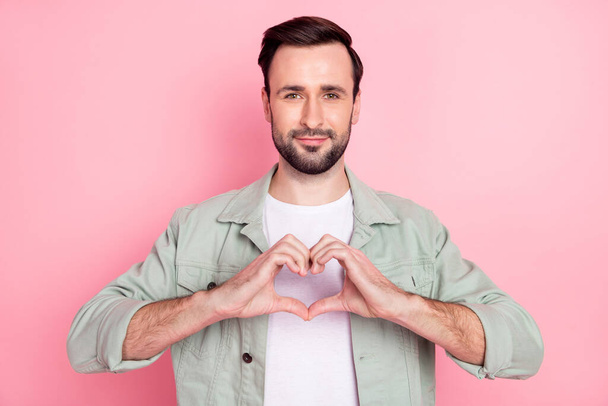 Portrait of attractive cheerful guy showing heart shape affection care isolated over pink pastel color background - Фото, изображение