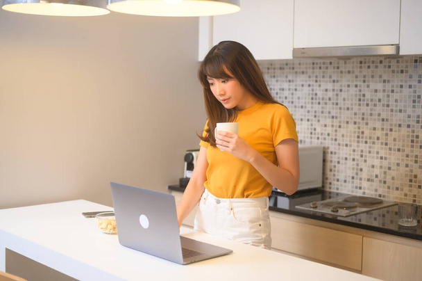 A young female working with her laptop and having a cup of coffee, life style and business concept - 写真・画像