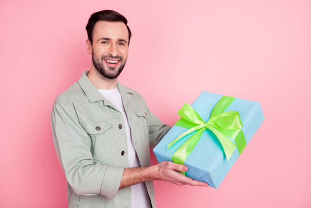 Portrait of attractive cheerful guy holding in hands gift dad father day occasion isolated over pink pastel color background - Foto, afbeelding
