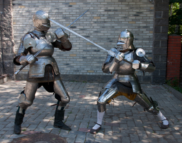 Deux chevaliers dans l'ancienne armure métallique debout près du mur de pierre
 - Photo, image