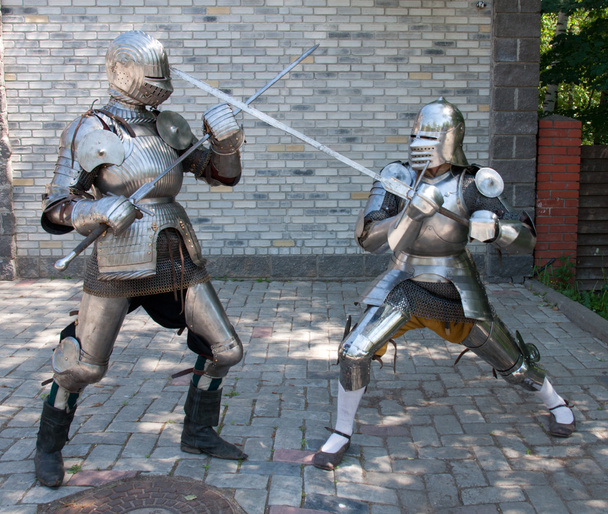 Two knights in the ancient metal armor standing near the stone wall - Foto, imagen