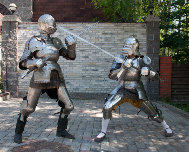 Deux chevaliers dans l'ancienne armure métallique debout près du mur de pierre
 - Photo, image