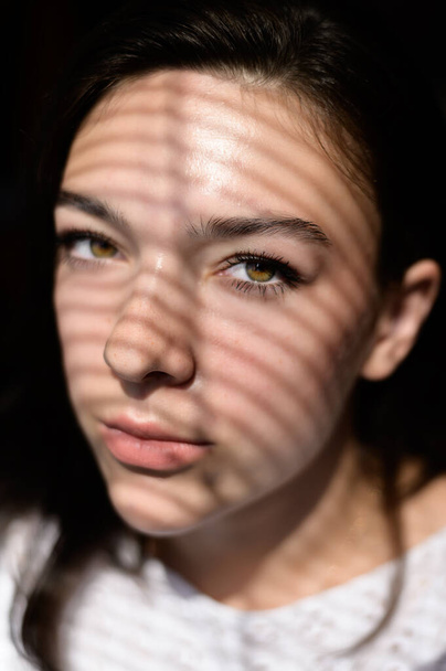 Beautiful young woman with striped shadow on her face. - Foto, imagen