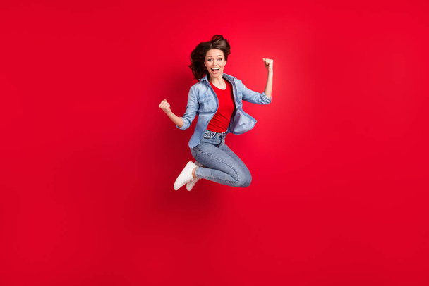 Ganzkörpergröße Foto von Mädchen aufspringen gestikulierend wie Sieger isoliert auf lebendigen roten Farbhintergrund mit Copyspace - Foto, Bild