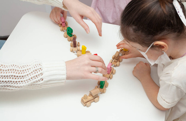 Two little girls in play constructs in the kindergarten. Little sisters play with a little train - Foto, imagen