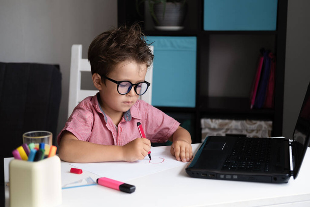  Poważny chłopiec kaukaski w okularach uczy się w domu, odrabiać lekcje - Zdjęcie, obraz