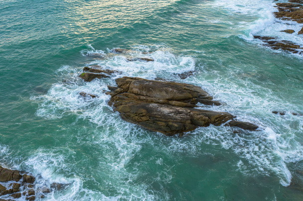 Αεροφωτογραφία των λευκών κυμάτων στο πράσινο της θάλασσας χτύπησε στα μεγάλα βράχια κατά τη διάρκεια της καλοκαιρινής ημέρας. - Φωτογραφία, εικόνα