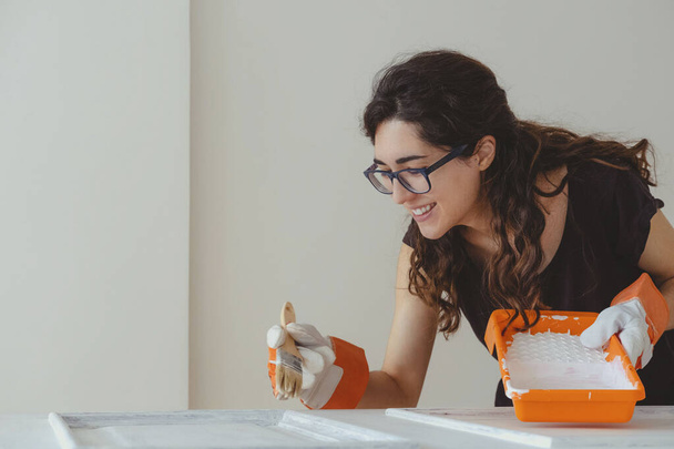 Jeune femme peignant une porte blanche avec un pinceau, concept fait maison. Rénovation maison - Photo, image