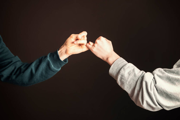 İki adam serçe parmaklarını tutarak barış yapıyor. - Fotoğraf, Görsel
