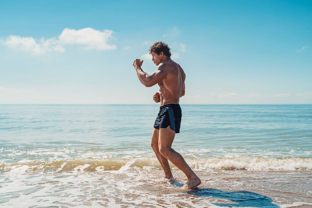 A muay thai or kickboxer training with shadow boxing outdoor at seashore - Fotoğraf, Görsel