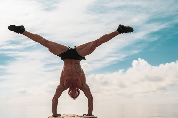 Young man is doing street workout. Handstand exercise, bodyweight - Photo, Image