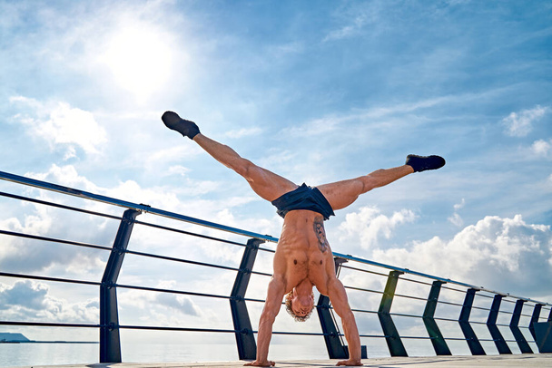 Young man is doing street workout. Handstand exercise, bodyweight - Photo, Image