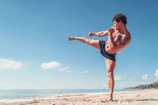 A muay thai or kickboxer training with shadow boxing outdoor at seashore - Valokuva, kuva
