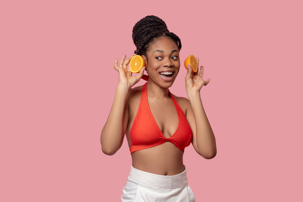 Young african american woman with slices of orange in hands - Foto, Imagen