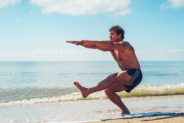 Muscular man doing exercise on beach. Body training - Zdjęcie, obraz