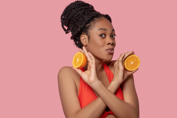 Cute african american woman with slices of orange in hands - Fotó, kép