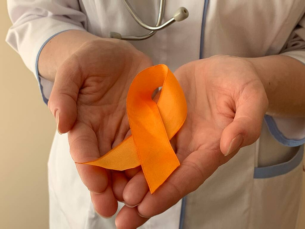 Fita laranja nas mãos de um médico. Esclerose múltipla, conceito de consciência oncológica.  - Foto, Imagem