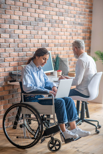 Handicapped young woman working with her colleague in the office - Foto, immagini