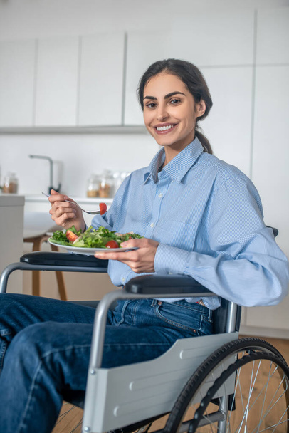 Positive handicapped young woman at home having lunch - 写真・画像