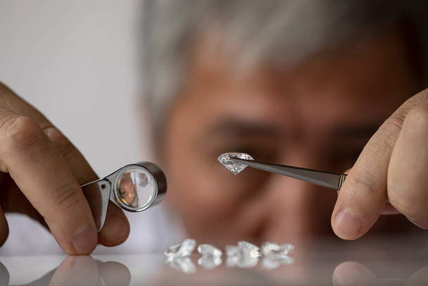 Close up of diamond dealers hands evaluating diamond at international jewelry exhibition - Foto, Bild