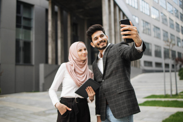 Muslim man and woman in formal wear taking selfie on mobile - Foto, Imagem