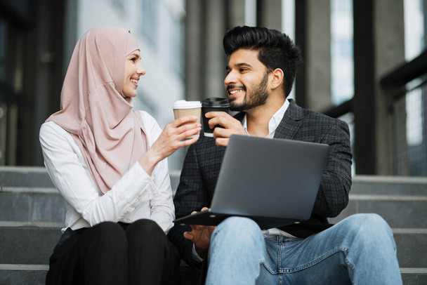Muslim coworkers toasting with cups of coffee outdoors - Foto, immagini