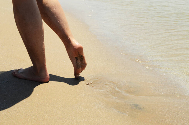 Primo piano dei piedi delle donne che camminano sulla spiaggia durante il sole diurno. - Foto, immagini