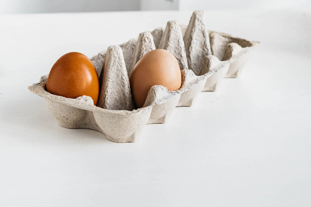 Minimalistyczna koncepcja żywności ekologicznej. Organiczne brązowe jaja wewnątrz i na zewnątrz pudełka - Zdjęcie, obraz