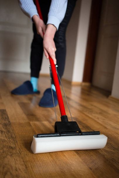 Young woman cleaning a wooden floor with a mop - Photo, image