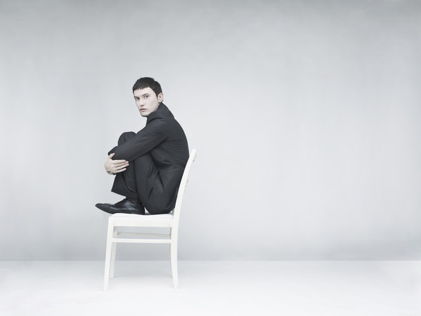 Man sitting on a white stool - Foto, Imagen