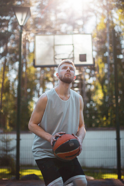 Professional handsome male american basketball player training on court outdoors in summer in sunlight - 写真・画像